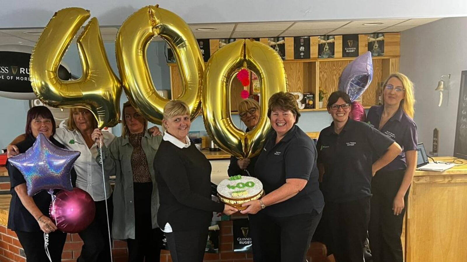 Team of people holding numbers 400 in balloons